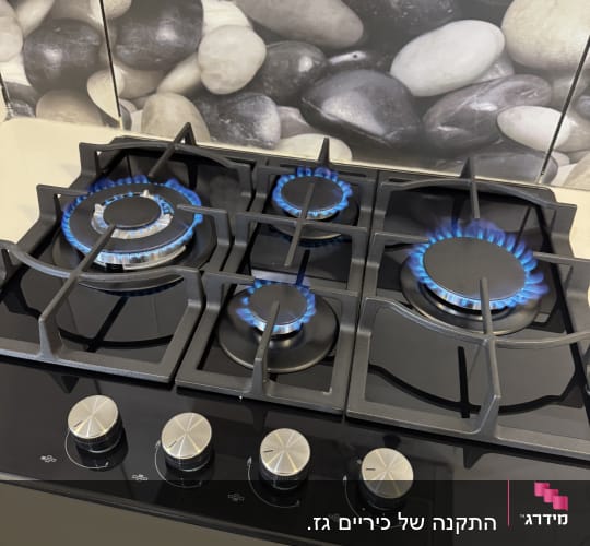 כיריים גז עם להבות כחולות על רקע אבנים דקורטיביות